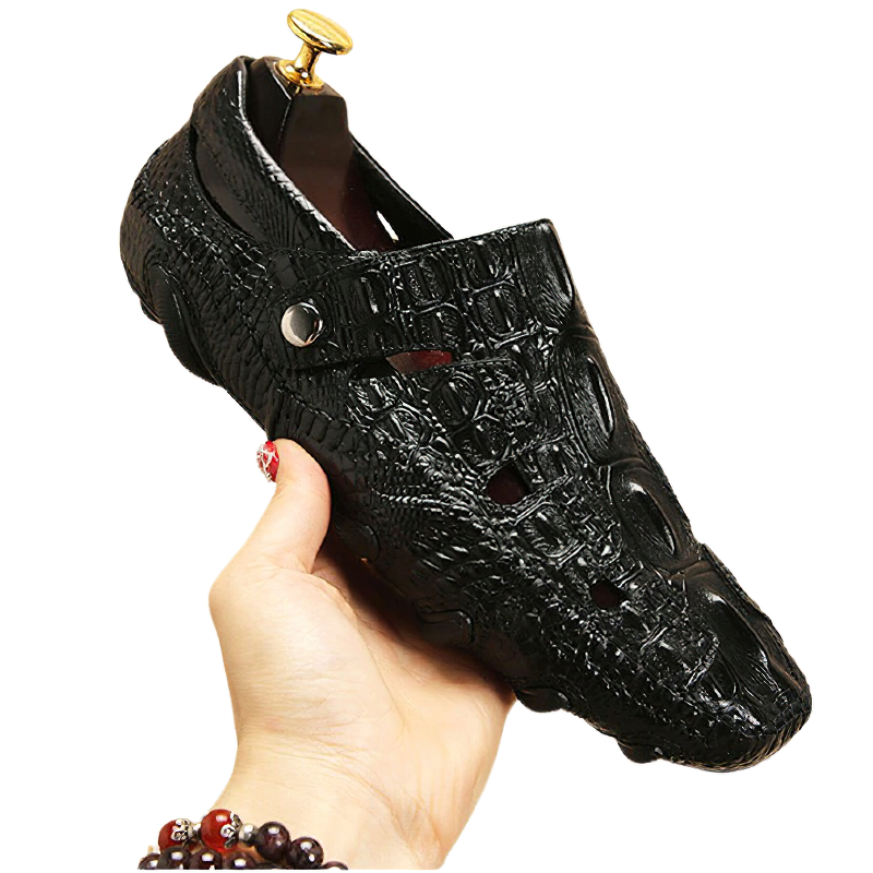 Stylish black genuine leather moccasins held in hand, featuring a unique crocodile texture design.