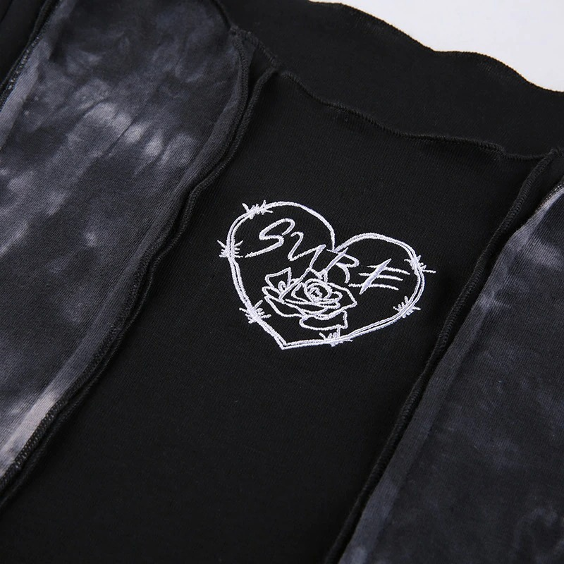 Close-up of stylish black crop top featuring a heart design and embroidered 'SURF' text, perfect for a punk aesthetic.