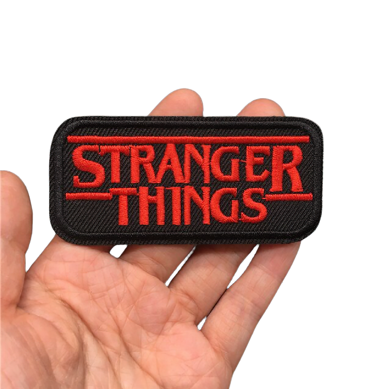 Hand holding a stylish black patch with red 'Stranger Things' logo, perfect for rock fashion and clothing decoration.