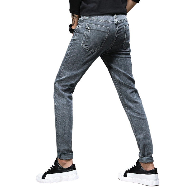 Stylish men's slim fit grey jeans showcased from the back, paired with trendy sneakers for a casual streetwear look.