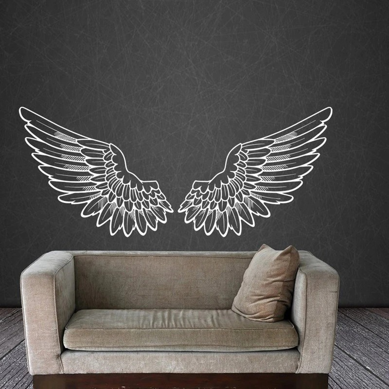 Stylish vinyl wall sticker of angel wings above a cozy sofa, perfect for home decor and enhancing personal space.