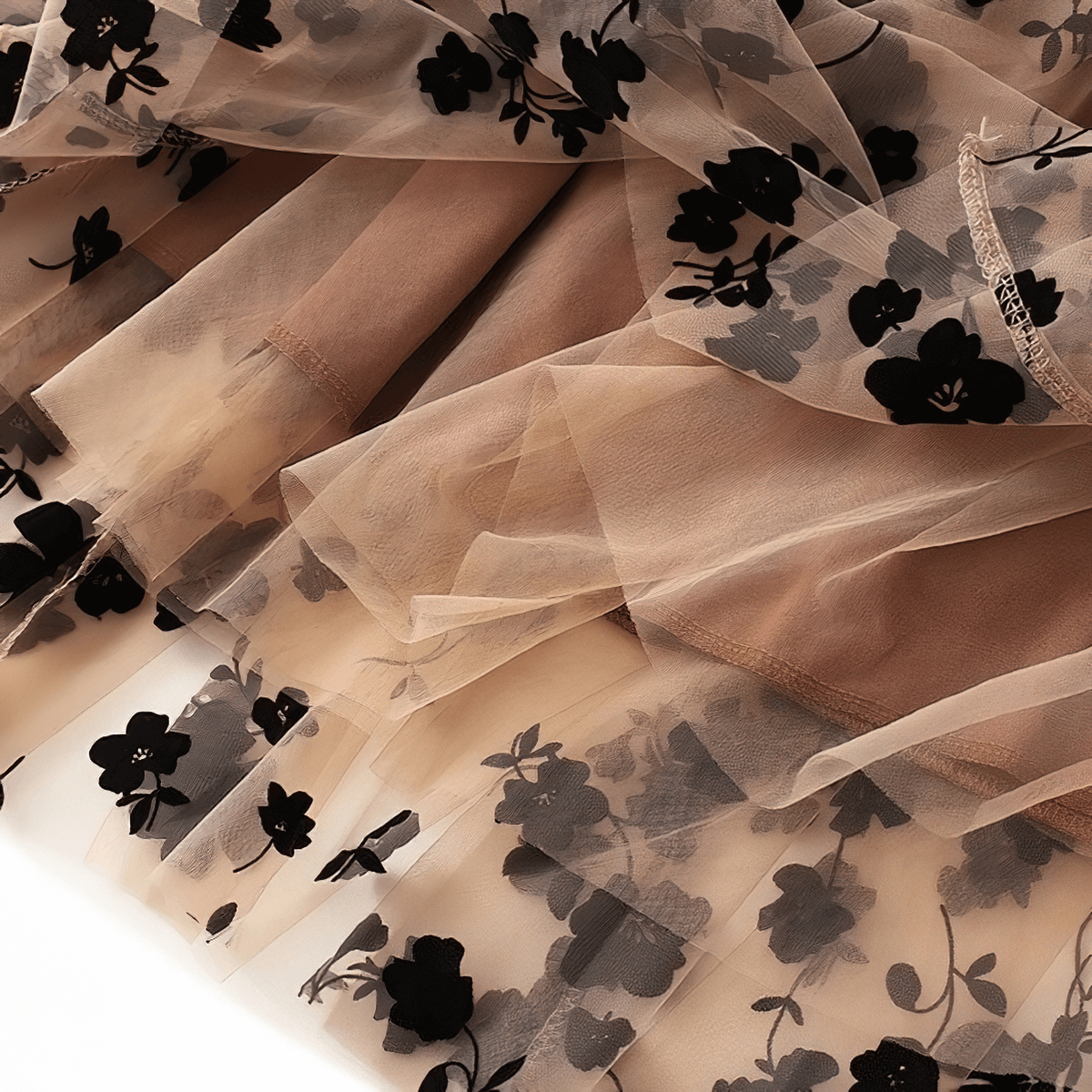 Close-up of stylish women's high waist midi skirt with black embroidered flowers on mesh tulle for a trendy look.