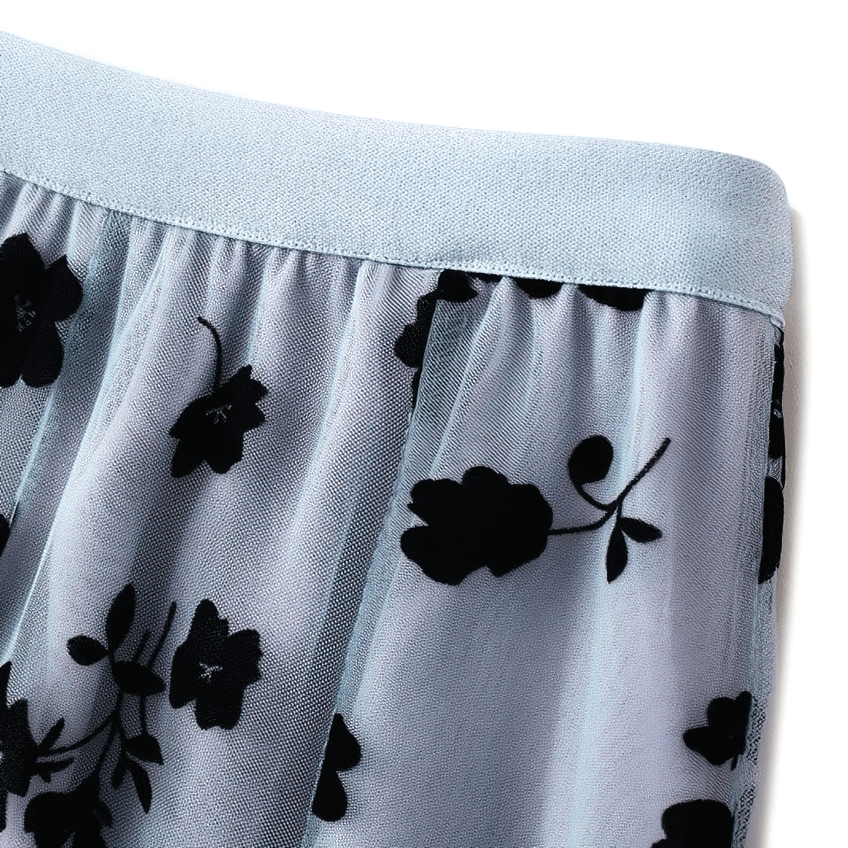 Close-up of stylish women's high waist skirt featuring embroidered flowers on soft mesh tulle fabric.