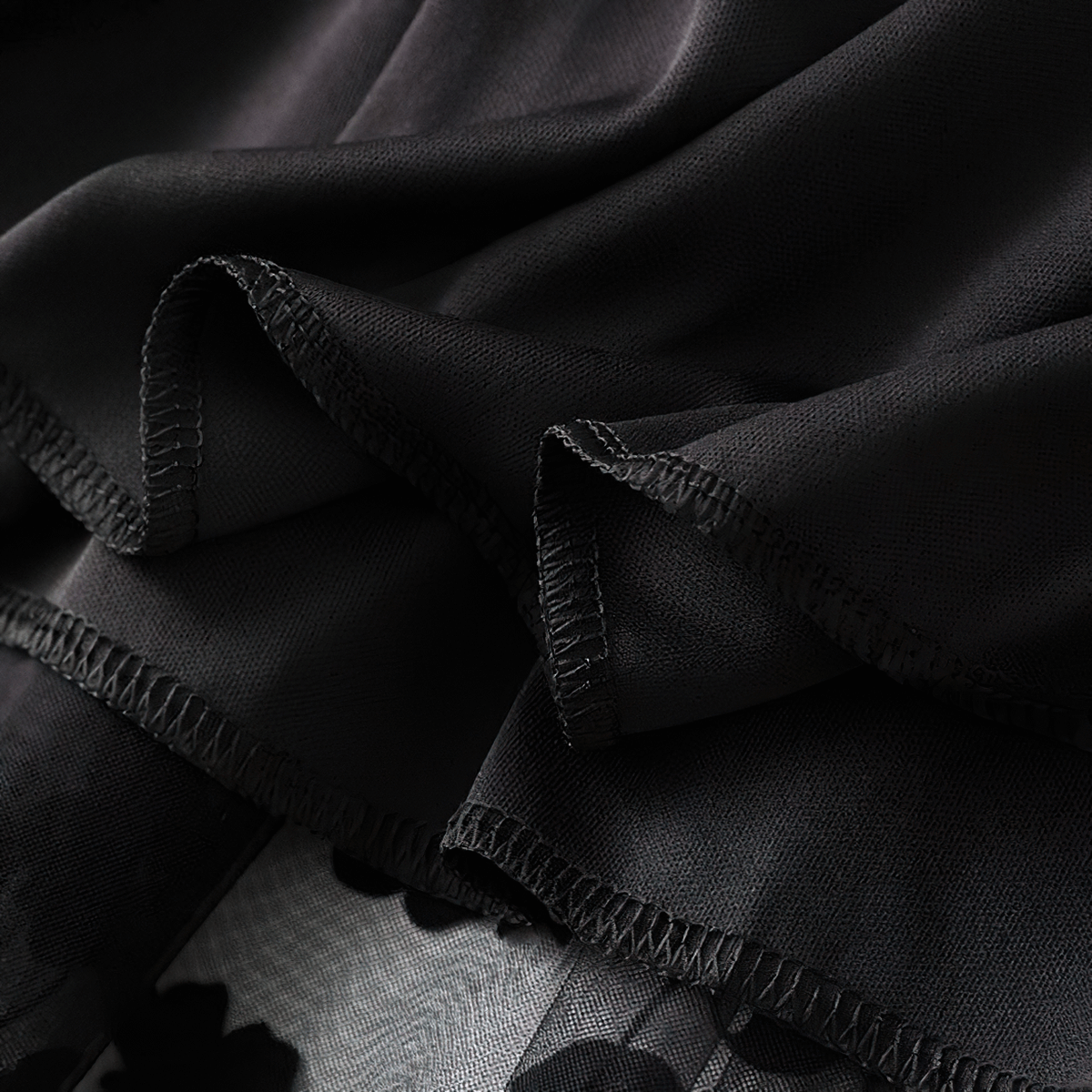 Close-up of the delicate fabric and floral print of a stylish black high waist skirt.