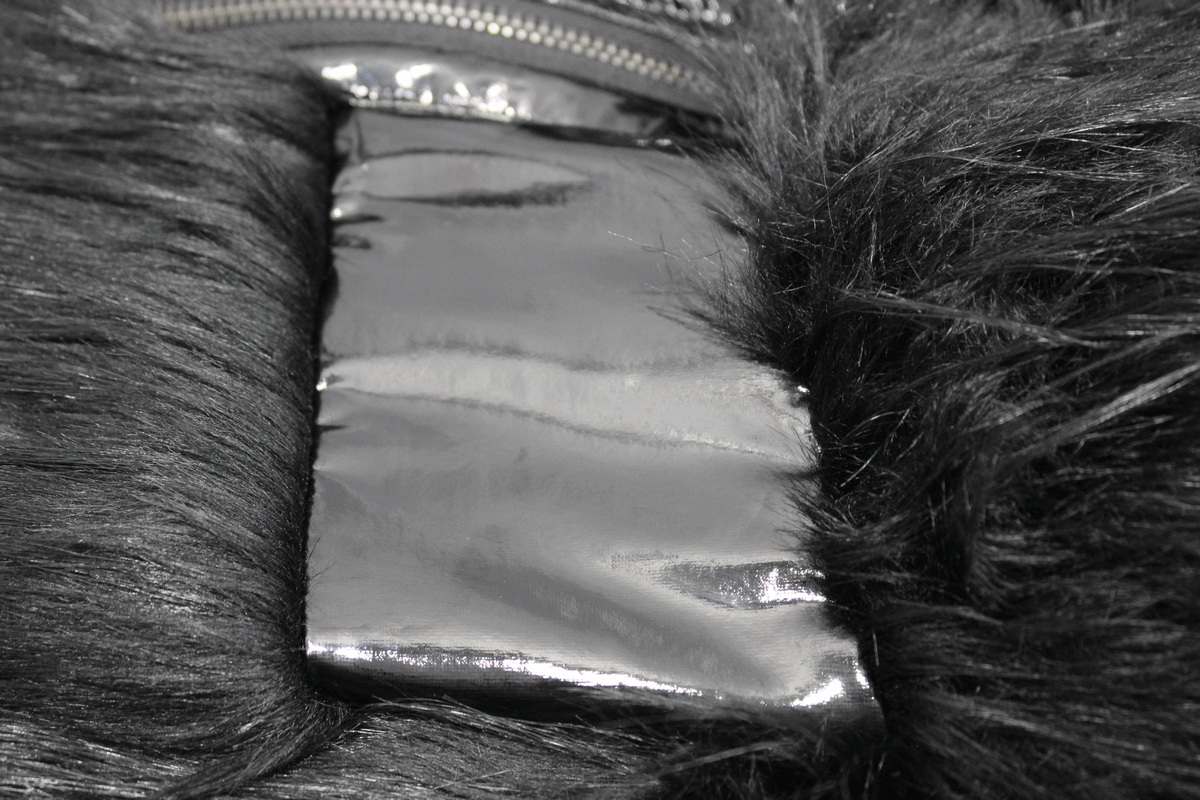 Close-up of luxurious fur and shiny PU leather details on a stylish women's gothic jacket.