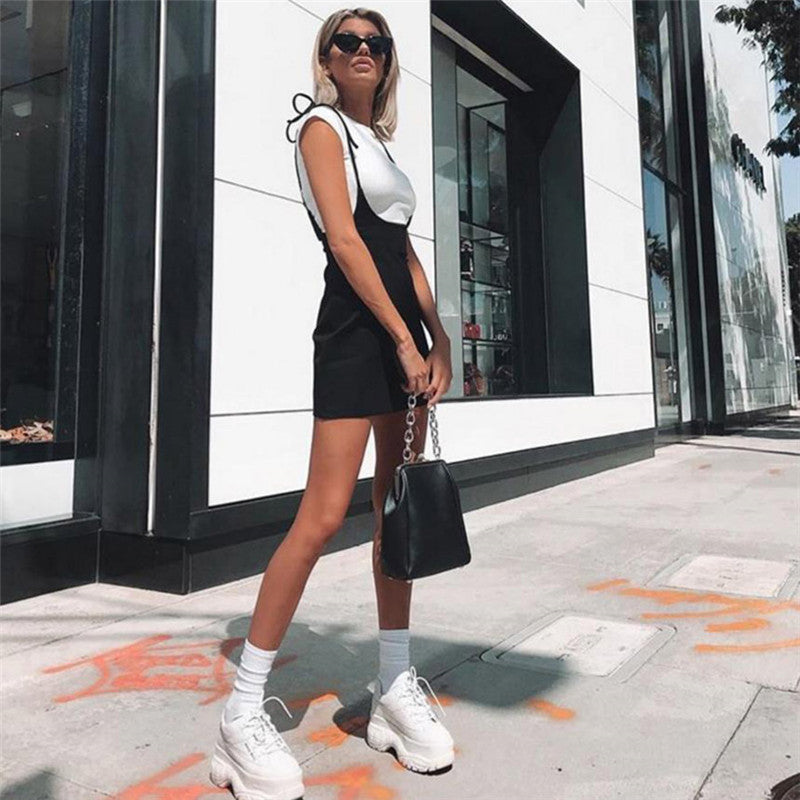 Stylish woman in a black skirt with shoulder straps, posing outdoors in alternative fashion.