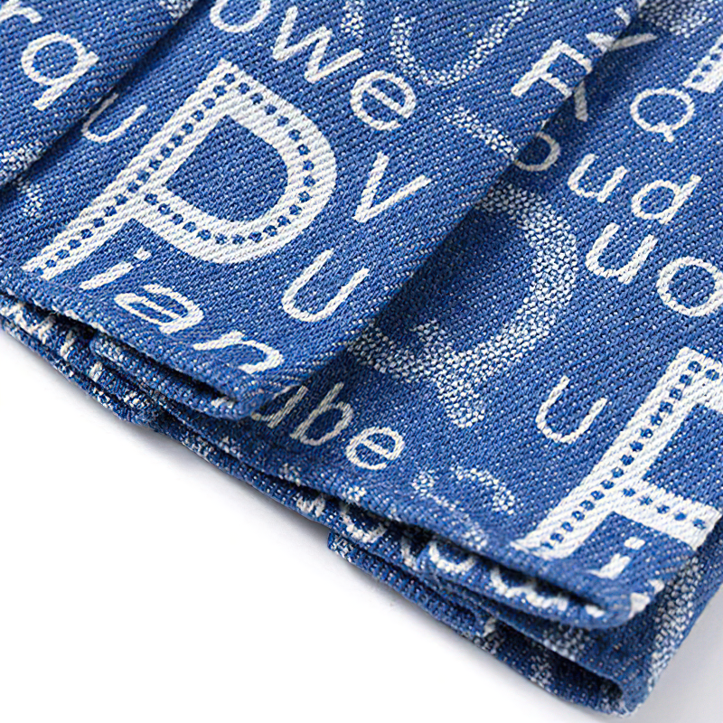 Close-up of a denim pleated skirt with printed letters and words, perfect for summer alternative fashion.