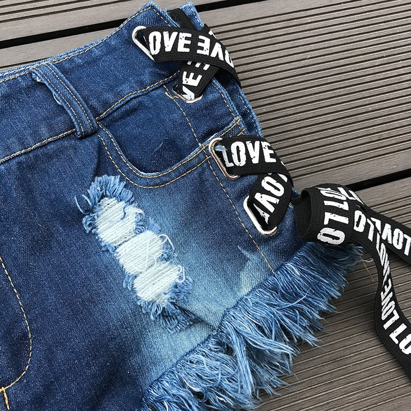 Close-up of vintage high waist denim shorts with lace-up design and frayed edges, perfect for summer fashion.