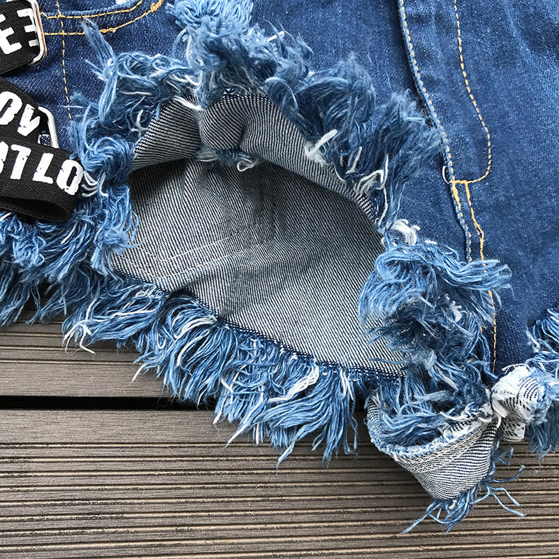 Close-up of the frayed hem and lace-up detail of vintage high waist denim shorts for women.