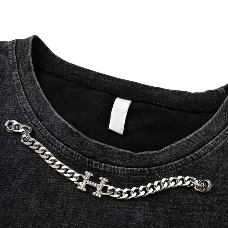 Close-up of the neck detail of a gothic ripped tank top featuring a silver chain and graphic design.
