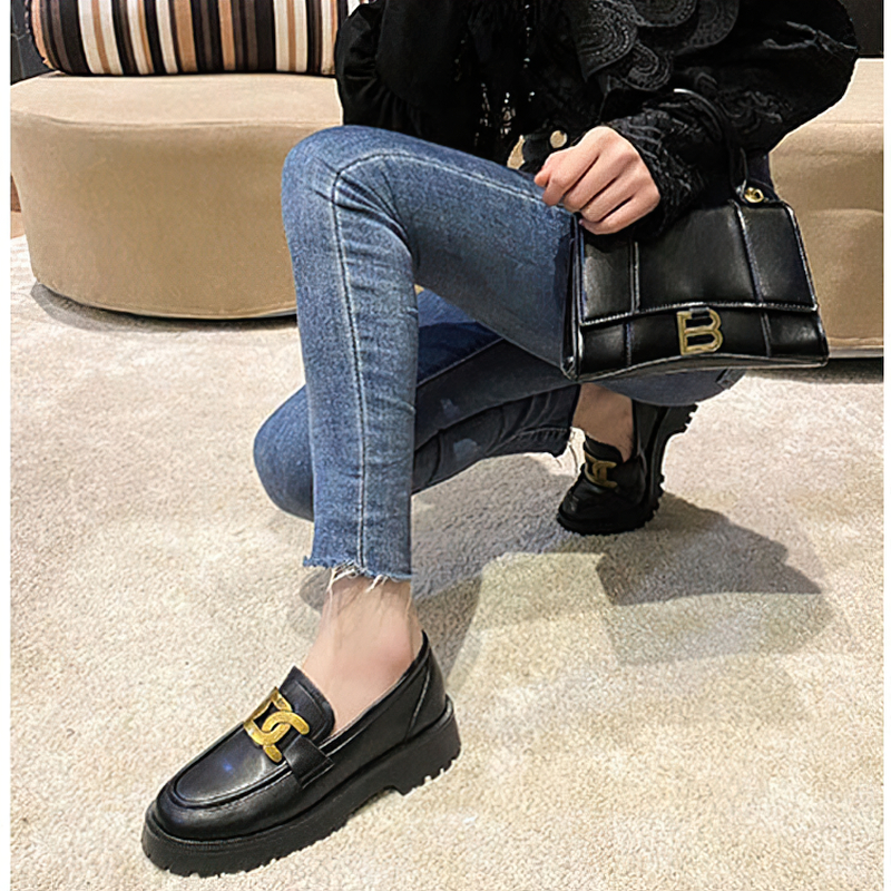 Fashionable black thick-soled loafers with gold chain, paired with jeans and stylish handbag, perfect for casual outings.