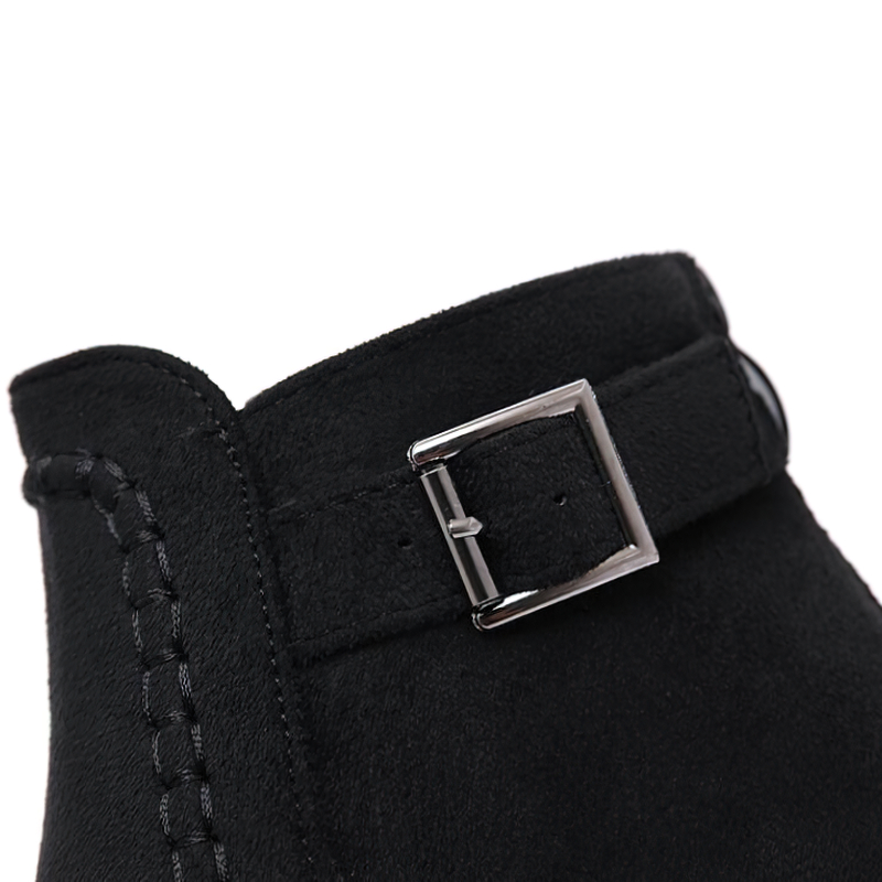 Close-up of trendy black ankle boot with buckle detail, highlighting the chic autumn style.