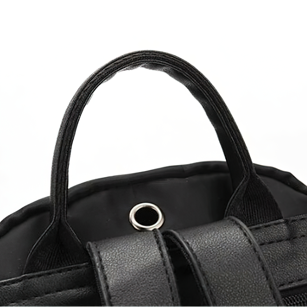 Close-up of black Oxford cloth backpack handle showcasing durable stitching and metal eyelet detail.