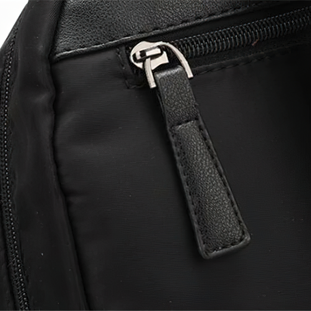 Close-up of a zipper pull on a sleek black oxford cloth backpack for women.