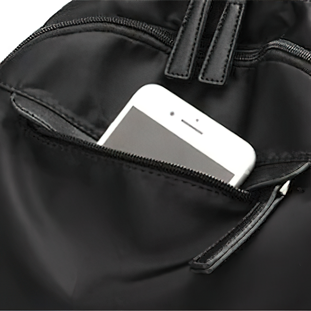 Close-up of phone tucked in zippered pocket of a trendy women's black backpack, showcasing practical and stylish storage.