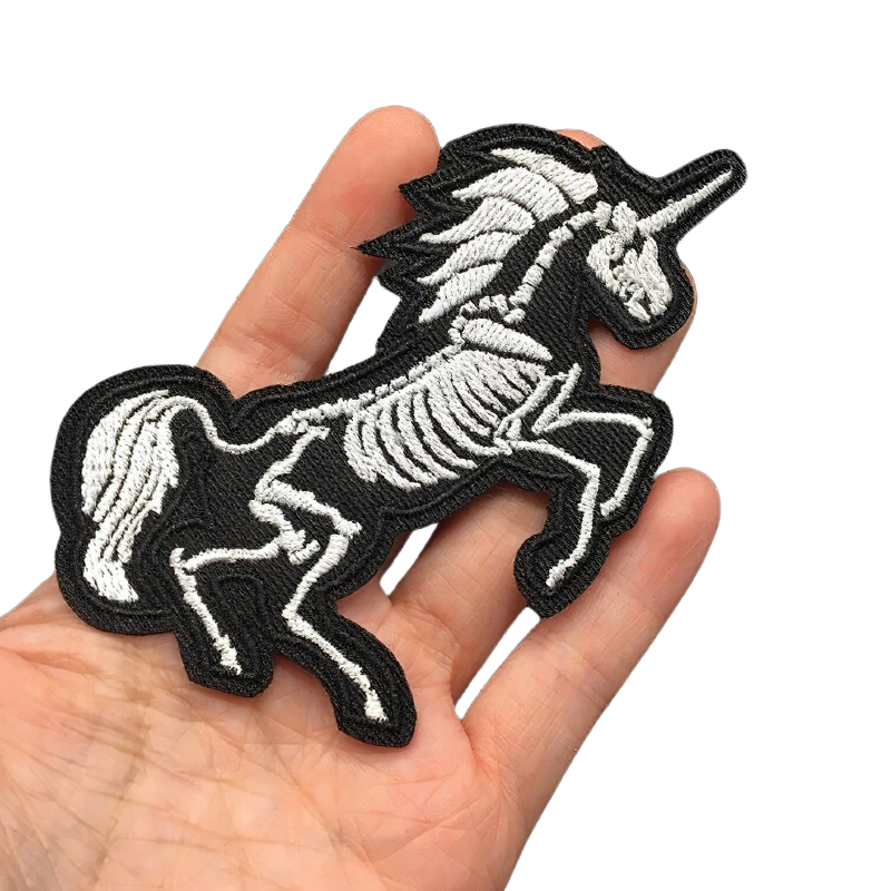 Unicorn skeleton patch held in hand, stylish rock style accessory for jackets, unisex embroidery design.