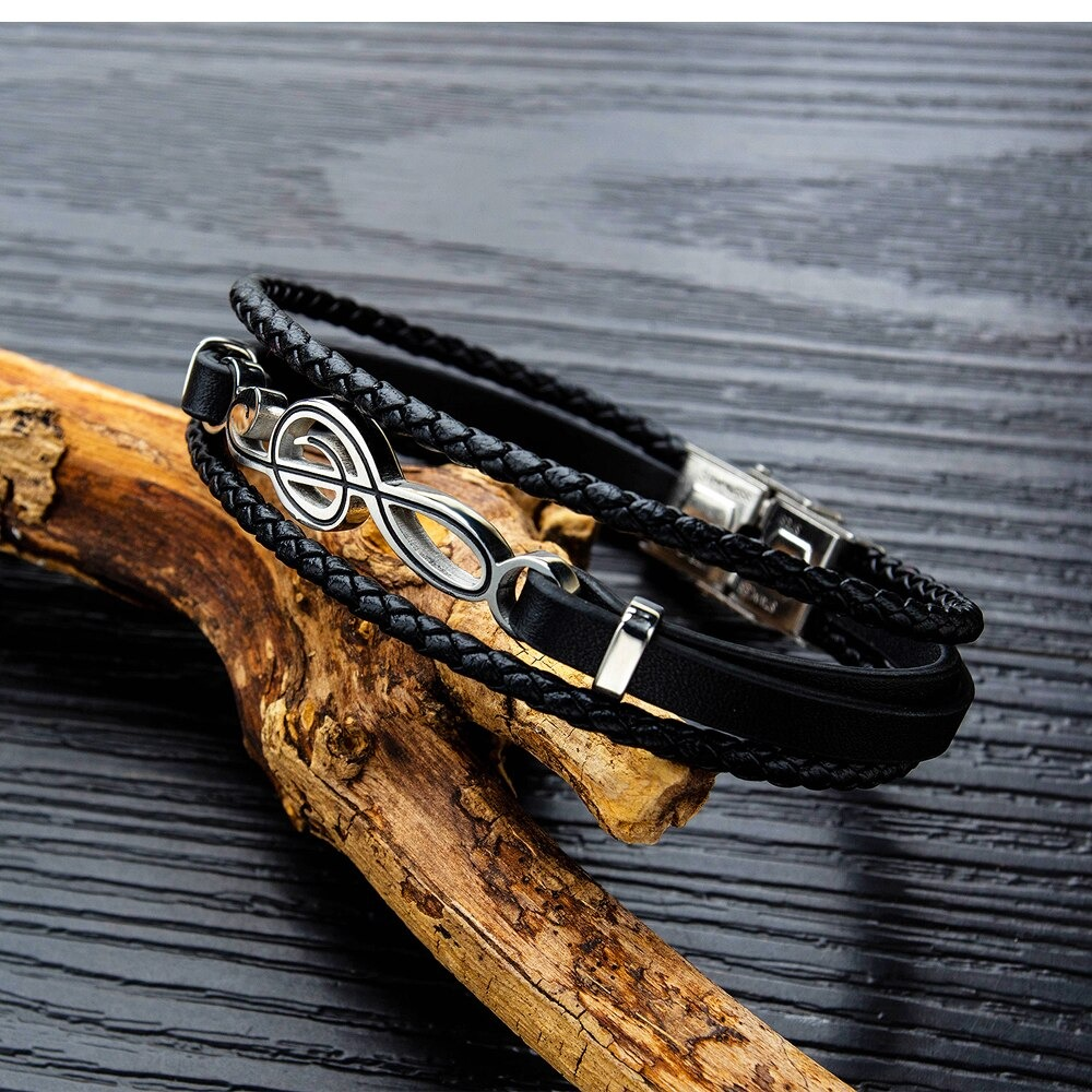 Stylish black PU leather bracelet featuring a silver musical note charm on rustic wood background.