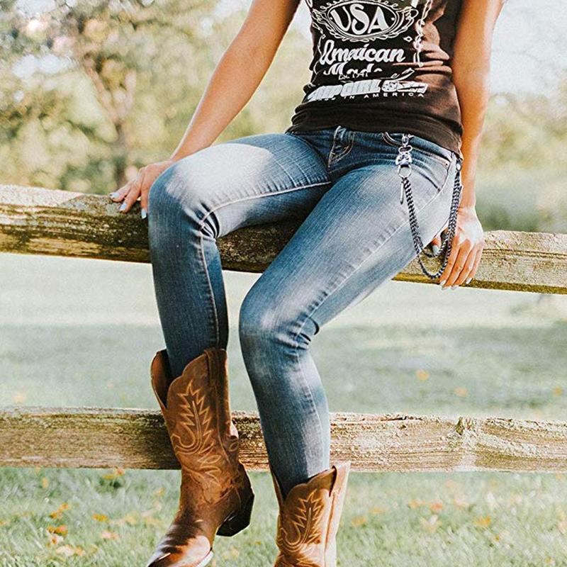 Unisex punk chain for pants styled with jeans and cowboy boots in a vintage outdoor setting.