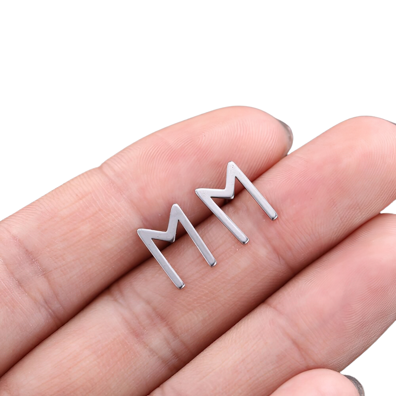 Hand holding unisex stainless steel vintage silver earrings, featuring elegant gothic MM design.