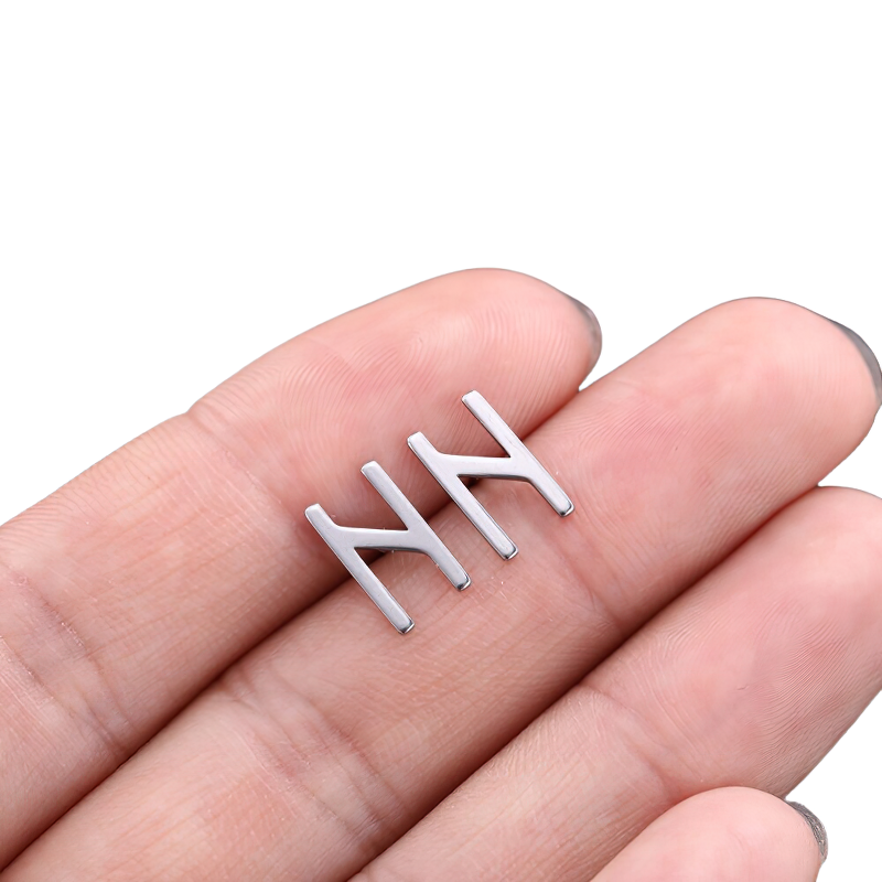 Hand holding unisex vintage stainless steel silver Gothic earrings design.