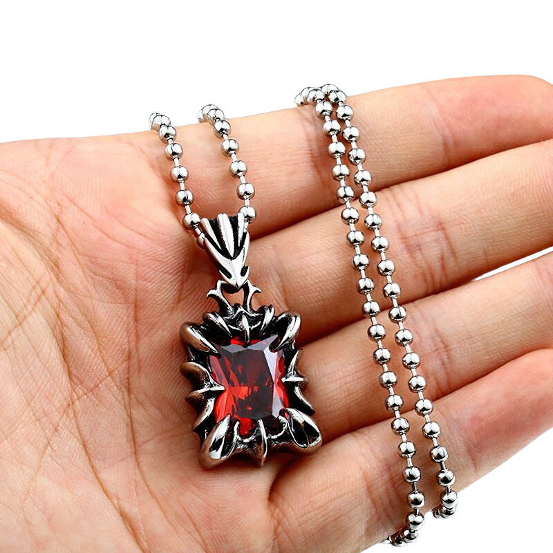 Unisex gothic style stainless steel pendant with red stone, showcasing a casual fashion accessory on a hand.