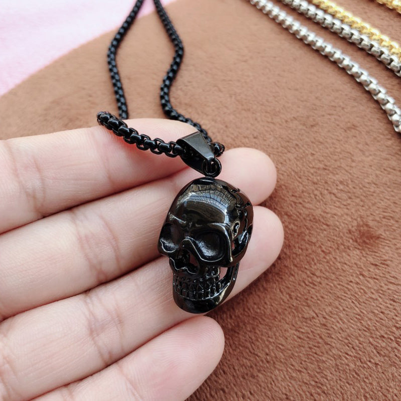 Unisex black stainless steel skull necklace pendant held in hand, perfect for rock style accessory lovers.