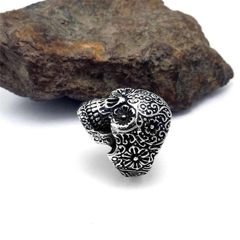 Vintage-style skull ring with intricate floral patterns, perfect for punk rock fashion. Metal accessories for an edgy look.
