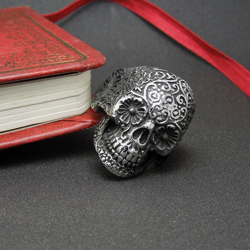 Intricate silver vampire skull ring beside a vintage book, perfect for rock punk fashion.