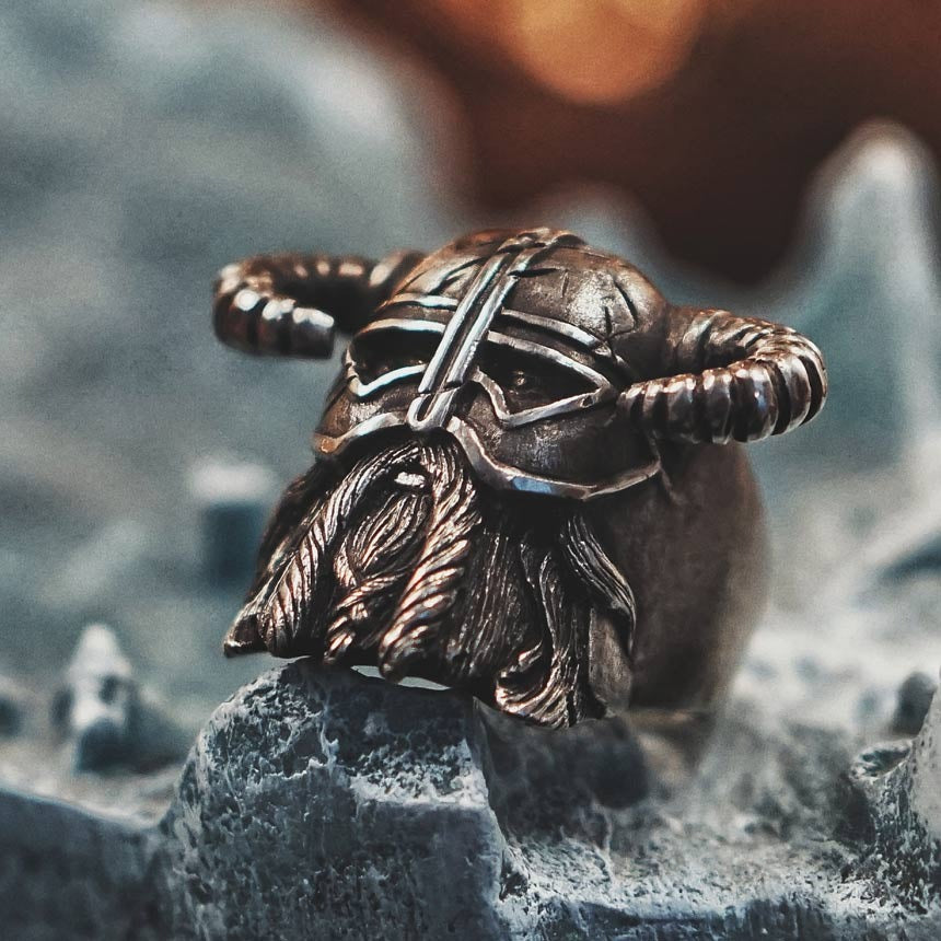 Viking helmet ring made of heavy stainless steel, showcasing unique Nordic warrior design on a rugged surface.