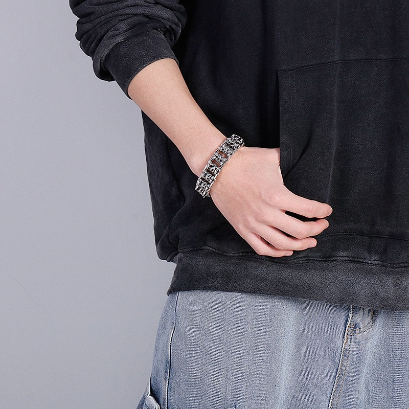 Stylish vintage ancient dragon totem bracelet on a man's wrist with punk style outfit.