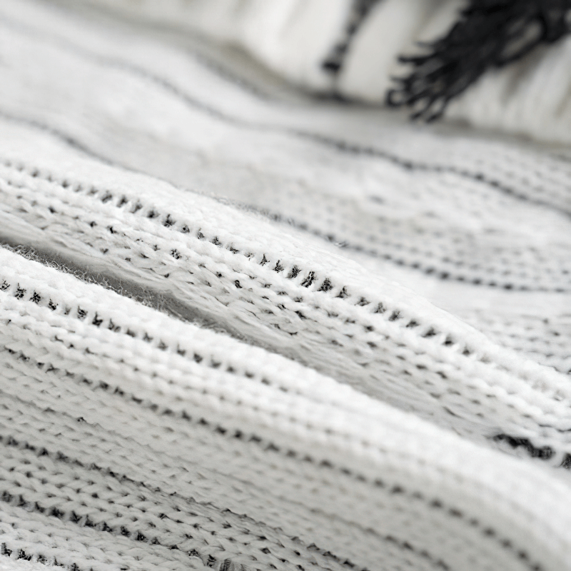 Close-up of a knitted white sweater featuring a textured and rippled design, perfect for a vintage casual look.