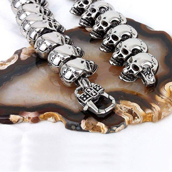 Vintage biker skeleton necklace on an agate surface, showcasing metallic skull designs in rock-inspired style.