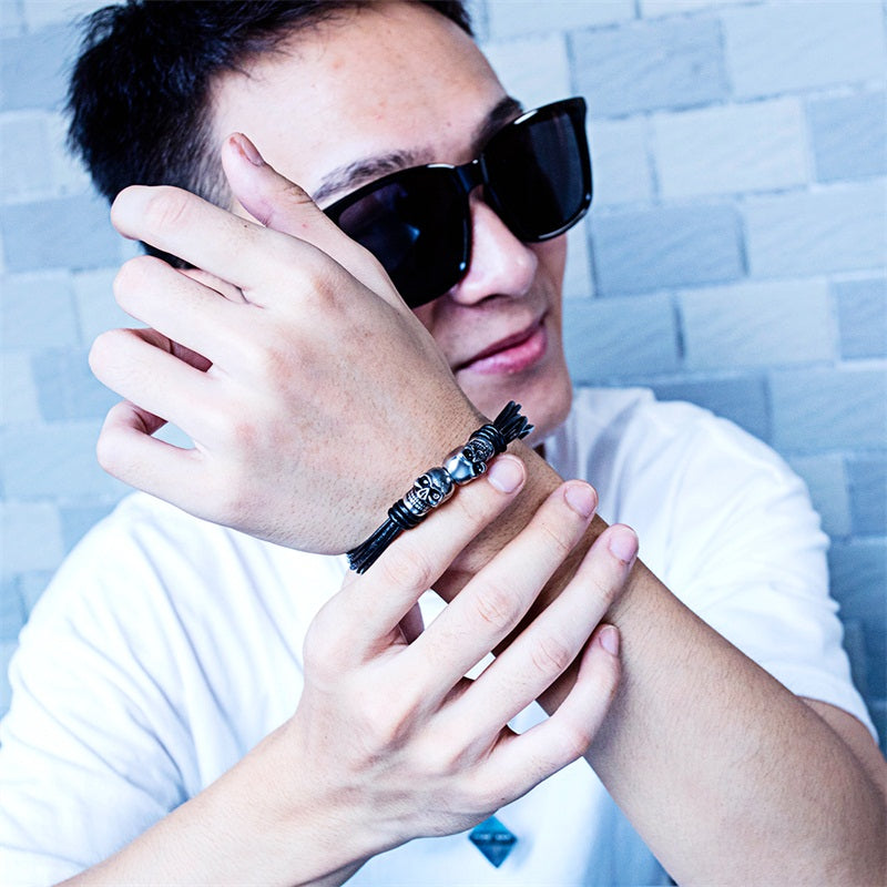 A stylish young man wearing a vintage black double skull bracelet, showcasing a unique rock style. Perfect unisex jewelry!