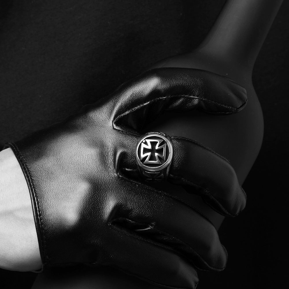 Black leather glove holding a vintage Celtic cross ring on a dark background, perfect for alternative fashion enthusiasts.