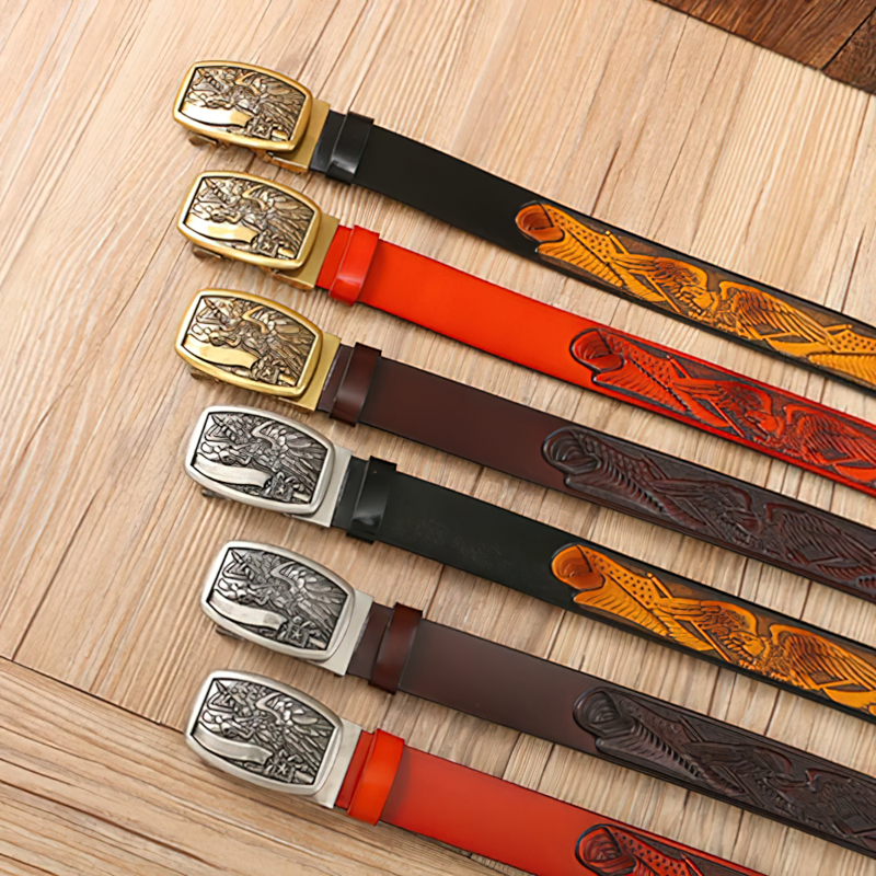 Vintage cowboy leather belts with eagle buckles in various colors displayed on wooden background.