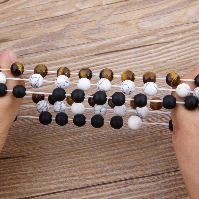 Men's vintage cubic zircon bracelet, featuring matte onyx stone and tiger eye beads, stylishly held by hands.