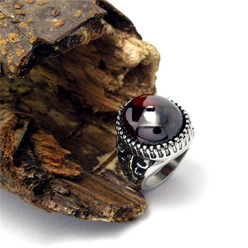 Vintage unisex stainless steel ring with a big red stone, set against rustic wood background.