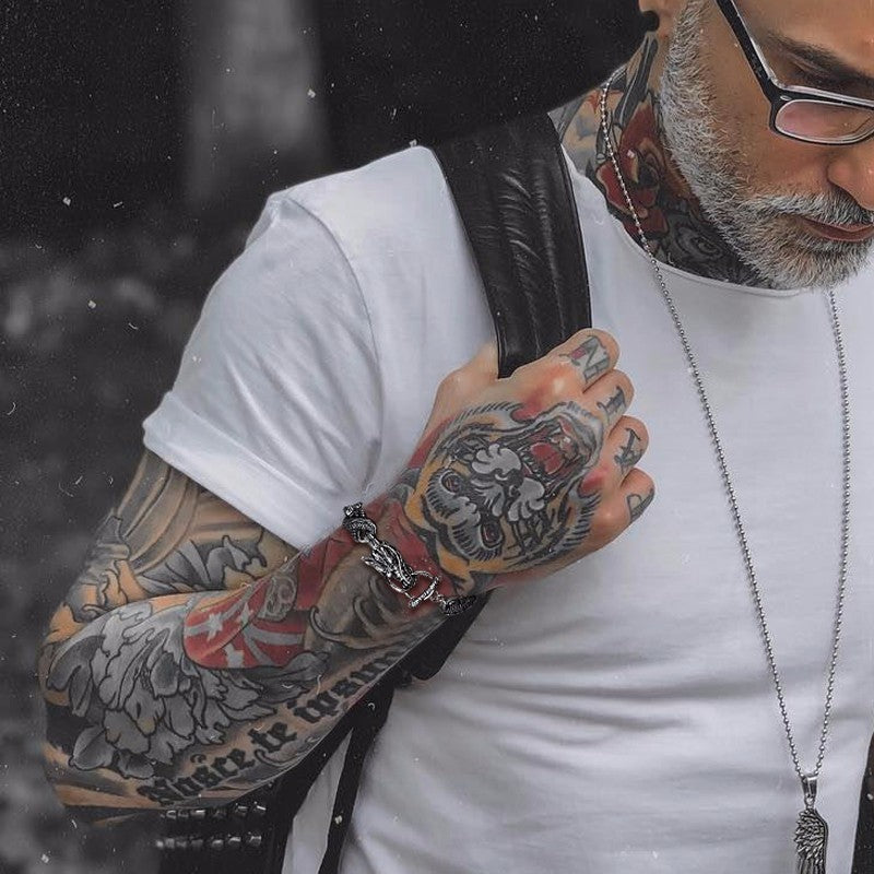 Stylish man with tattoos wearing a vintage dragon bracelet and white t-shirt, showcasing punk fashion and accessories.