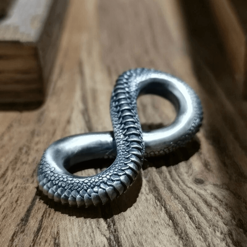 Vintage snake pendant designed in an infinity shape, showcasing intricate carving detail on wood background.