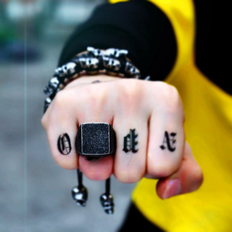 Man's hand showcasing a vintage square design stainless steel ring and skull bracelet for bold biker fashion.