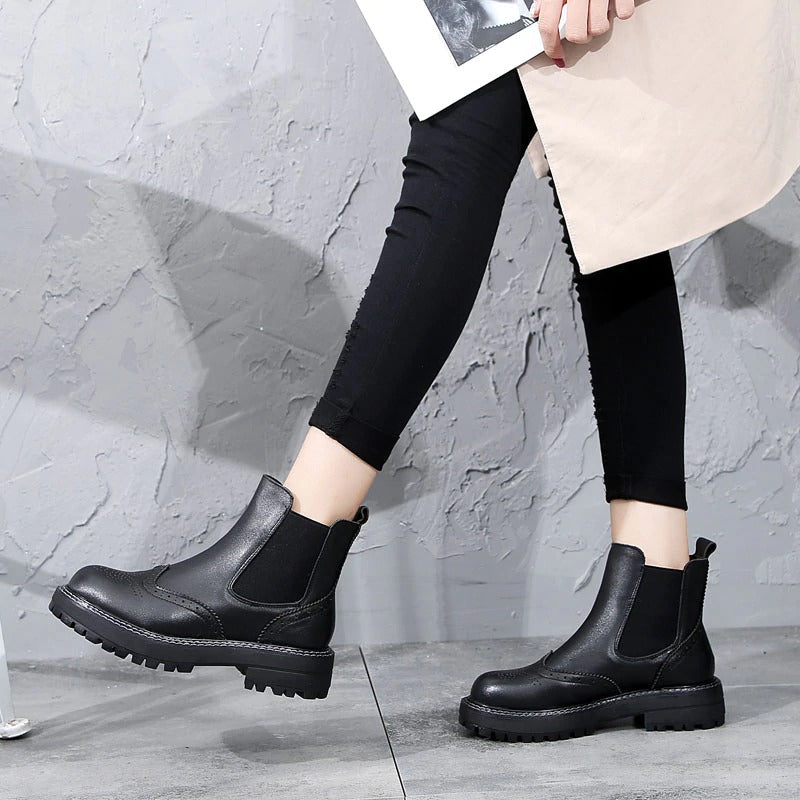 Vintage genuine leather flat ankle boots in black, styled with leggings and a modern aesthetic backdrop.