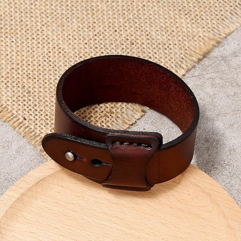 Vintage genuine leather wide cuff bracelet on a wooden surface, showcasing a minimalist punk design for unisex wear.