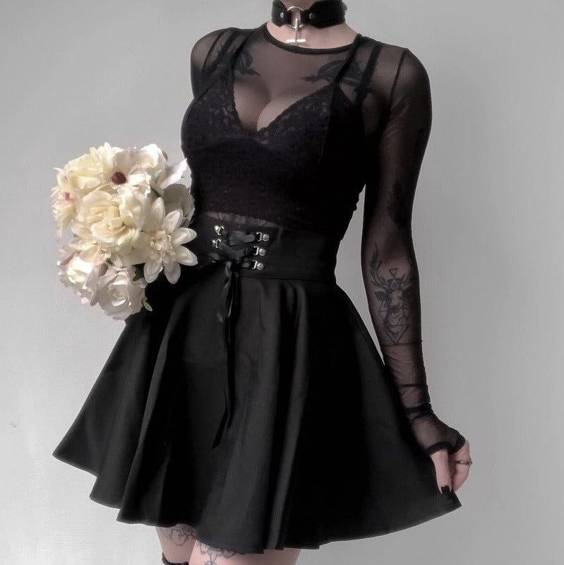 Model wearing a vintage gothic pleated skirt with lace-up rivets, styled with a sheer top and holding flowers.