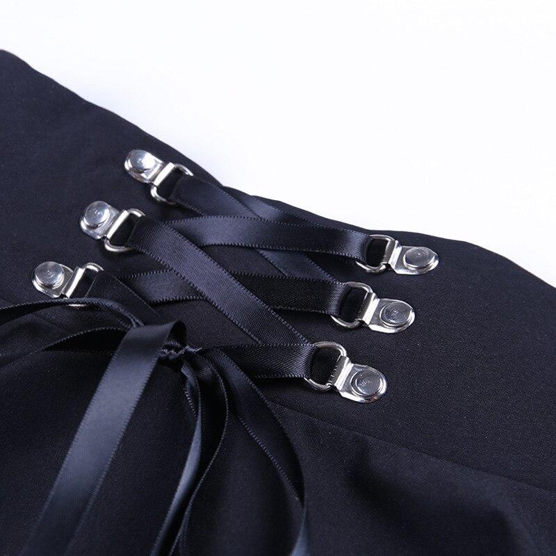 Close-up of vintage gothic pleated skirt showcasing lace-up design and silver rivets on a black fabric background.