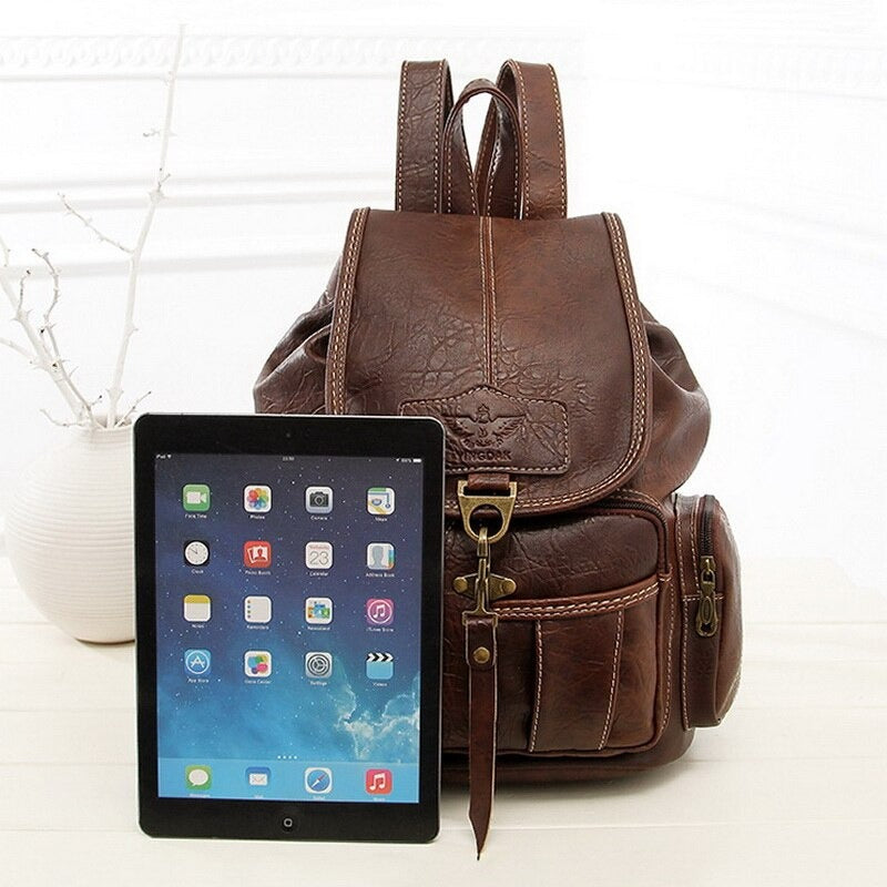 Vintage PU leather women's backpack next to tablet, perfect for alternative fashion and daily adventures.