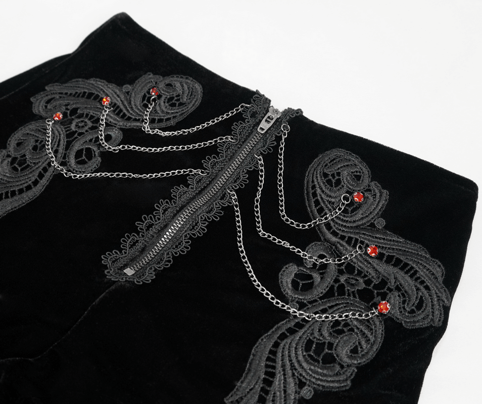 Close-up of vintage black velvet shorts with gothic lace appliqué and red embellishments, perfect for a unique look.