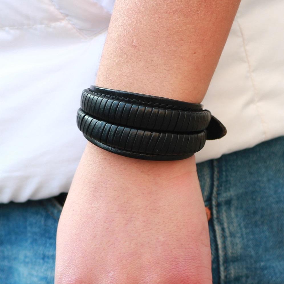 Vintage black leather bracelet cuff on wrist, stylish double wide design perfect for casual or outdoor activities.