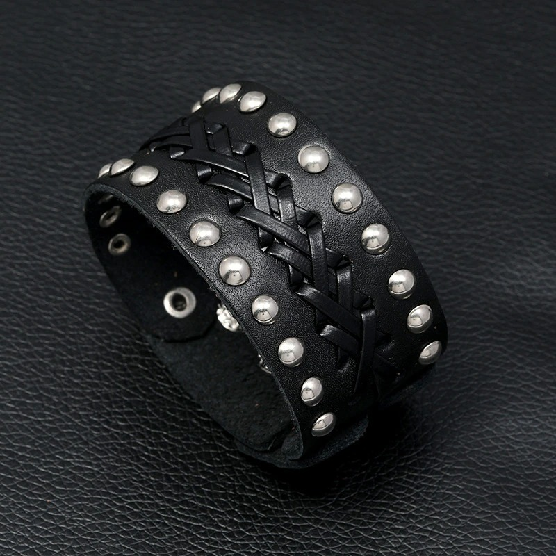 Wide vintage male leather bracelet with silver rivets, manual weave, in punk rock style on a black background.