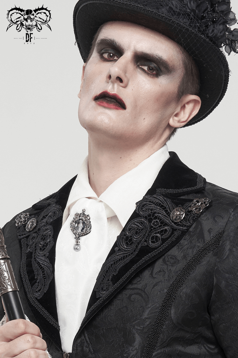 Gothic vintage male model in black suit and white tie with crystal brooch, showcasing a dramatic style.
