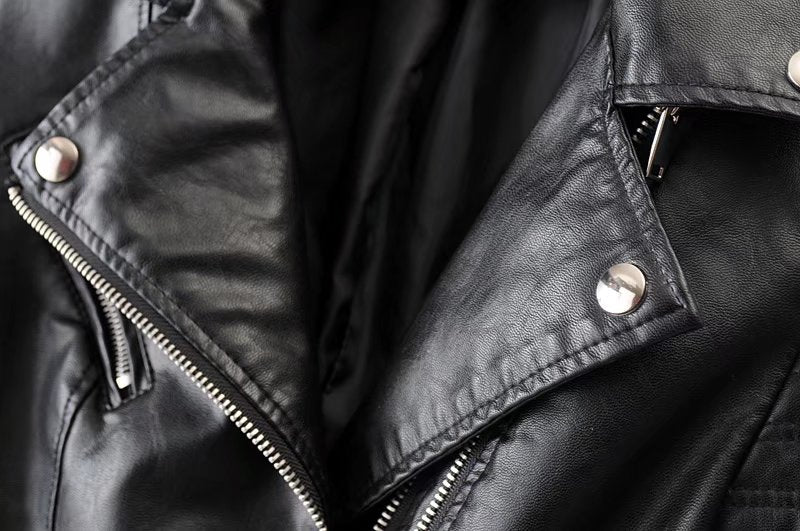 Close-up of women's vintage faux leather motorcycle jacket featuring stylish zippers and rivets for a bold biker look.